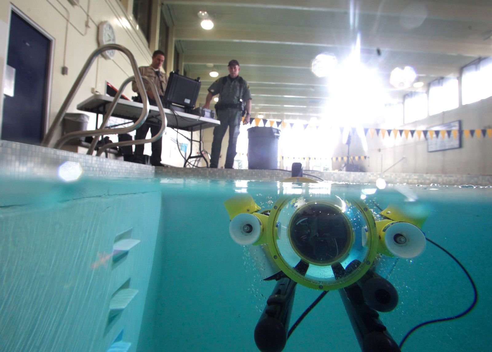 The Snohomish County Sheriff's Office's newly acquired SeaLion-2 underwater robot, dubbed "Batman" by deputies, cruises in a South Everett swimming pool last week. Its controllers are seen above the robot. Photo: Mark Mulligan / The Herald