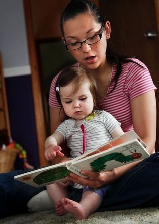Dan Bates / The HeraldAisha Bone, 25, reads "The Very Hungry Caterpillar" to her daughter, Paige, who turned 1 on Friday. Bone is expecting her second baby in December and became interested in Providence Regional Medical Center Everett's new prenatal program offering support and education.