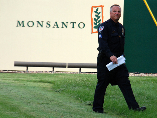 Officer on patrol guards Monsanto logo at Occupy Monsanto protest. Photo: Langelle Photo for GJEP