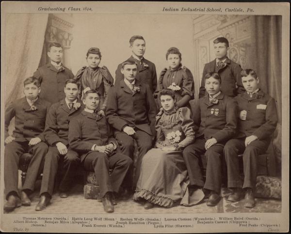 Archives and Special Collections, Dickinson College, Carlisle, PAThe caption reads: Graduating Class, 1892. Indian Industrial School, Carlisle, Pa. Thomas Metoxen (Oneida.) Hattie Long Wolf (Sioux.) Reuben Wolfe (Omaha.) Luzena Choteau (Wyandotte.) William Baird (Oneida.) Albert Bishop, (Seneca.) Benajah Miles (Arapahoe.) Joseph Hamilton (Piegan.) Benjamin Caswell (Chippewa.) Frank Everett (Wichita.) Lydia Flint (Shawnee.) Fred Peake (Chippewa.) Photographer: John N. Choate, Carlisle, PA