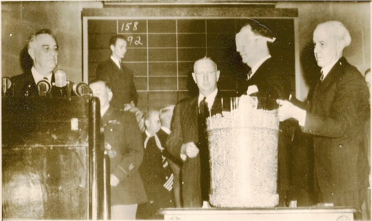 October 29, 1940, U.S. Attorney General Robert Jackson draws the third draft lottery number from a large jar, as President Franklin Roosevelt looks on. (Courtesy nationalww2museum.org)