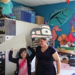 Art and Crafts Specialist, Astrid is displaying a final creation of a eagle hat that kids are making like tribal member Tauveiy Chrismay.