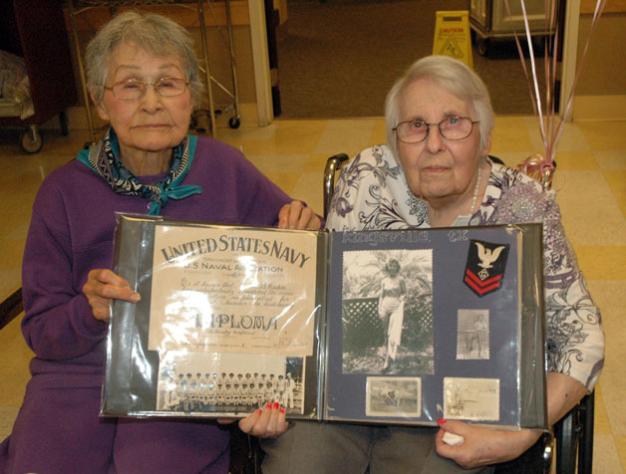 Kirk BoxleitnerBlanche Coy James, left, helps her childhood friend, fellow 90-year-old Barbara Caton VanderVeer, hold up VanderVeer’s memorabilia from serving in the U.S. Navy during World War II.