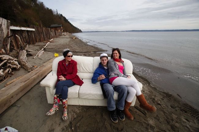 Dan Bates / The Herald(From left) Susan Marshall, Tanner Bellows and Karrington Jessup relax on a comfy white leather couch, just above the tide line, while they watch the house moving.