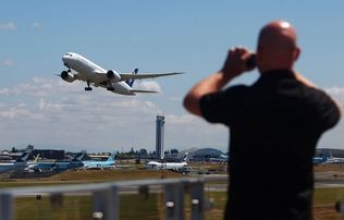 Mark Mulligan / The HeraldA European visitor at the Future of Flight Museum in Mukilteo photographs a Boeing 787 lifting off from a runway at Paine Field.