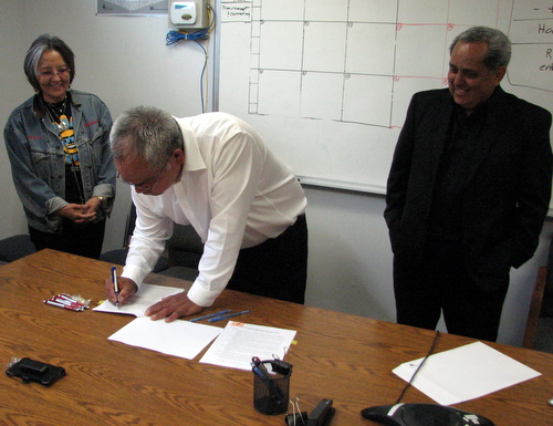 Sealaska vice-chair Rosita Worl and chair Albert Kookesh look on as STA Council chair Michael Baines signs a management agreement for Redoubt Falls.