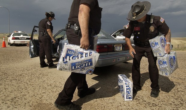 This 2005 file photo shows Pine Ridge police officers Mirian Laybad (left), Sgt. Oscar Hudspeth and Lt. Mitch Wisecarver confiscate cases of beer at a checkpoint just north of Whiteclay. (Lincoln Journal Star photo)