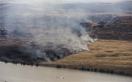 This Monday, July 29, 2013 photo shows the Colockum Pass fire burning in the mountains which has also burned its way down to the banks of the Columbia River. The Colockum Pass fire has grown to more than 10 square miles burning 5 five homes in addition to other structures 20 miles south of Wenatchee. (AP Photo/The Seattle Times, Steve Ringman)