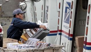 Letter carrier Diosdado Gabnat moves boxes of mail into his truck at a post office in Seattle.