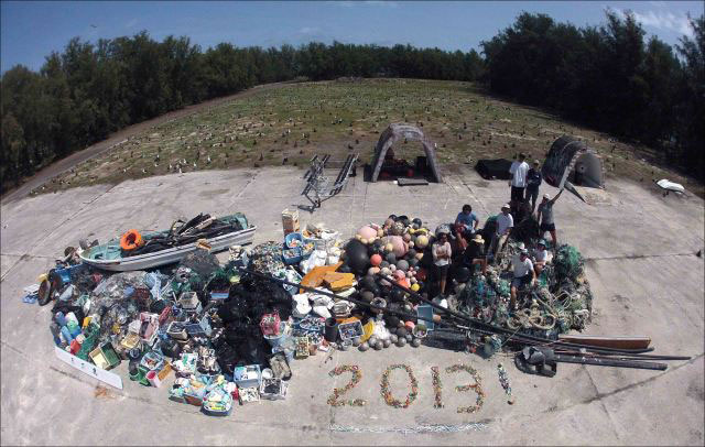 James Morioka, Kerrie Krosky, Kristen Kelly, Tomoko Acoba, Kevin O’Brien, Kerry Reardon, Edmund Coccagna, Joao Garriques, and Russell Reardon (clockwise from upper right) pose on April 18 atop the large, 13,795-kilogram (about 30,400 lbs) pile of fishing gear and plastic debris collected during their 2013 cleanup effort around Midway Atoll.Credit: NOAA photo by Edmund Coccagna