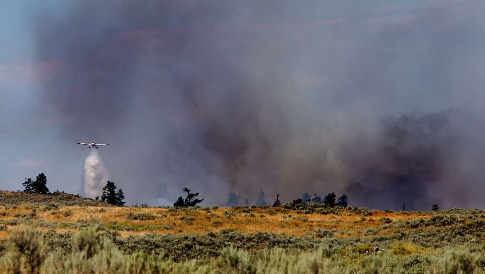 A plane drops water on the edge of a fire near Omak Lake east of Okanogan Tuesday afternoon. World photo/Don Seabrook