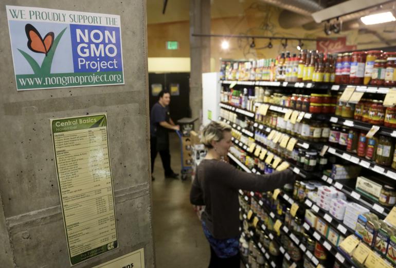 Employees stock shelves near a sign supporting non genetically modified organisms, or GMO, at the Central Co-op in Seattle on Oct. 29, 2013. Reuters/Jason Redmond 