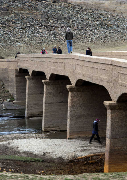 Visitors walk over Salmon Falls Bridge, normally submerged, at Folsom Lake in California last month. California began hauling 30 million young chinook salmon hundreds of miles toward the Pacific Ocean in tanker trucks to save the fishing industry after a record drought left rivers too low for migration.KEN JAMES — BLOOMBERG NEWS 