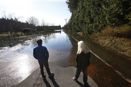 Genna Martin / The HeraldPatricia Flajole (right) and son Pat look out over a flooded Highway 530 east of the Oso mudslide area on March 23, the day after the slide. The Flajole family owns a cabin just east of the slide area. The water, which had backed up because of river blockage, has mostly receded since then.