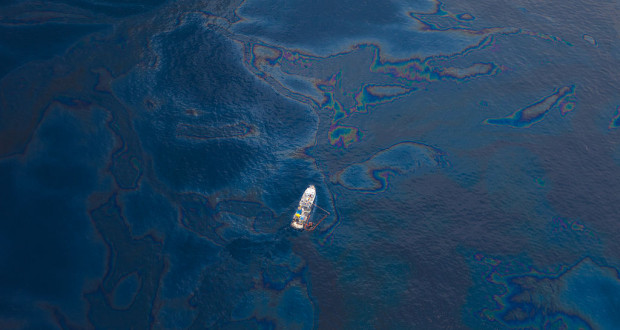 A ship floats amongst a sea of spilled oil in the Gulf of Mexico after the BP Deepwater Horizon oil spill disaster. By kris krüg via Wikimedia Commons