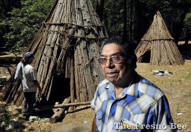 Les James, right, who is Miwuk-Chukchansi, beside two examples of traditional housing called umachas with tribal elder Bill Tucker, a Miwuk-Paiute, seen to the left, on a tour of a village site in Yosemite Valley just a few yards from the main loop road driven by thousands of visitors. A umacha is constructed with a frame of cedar poles covered by cedar bark using wild grape vines to tie joints together, according to Tucker and James. Photographed on Monday, June 9, 2014 in Yosemite National Park. ERIC PAUL ZAMORA — Fresno Bee Staff Photo