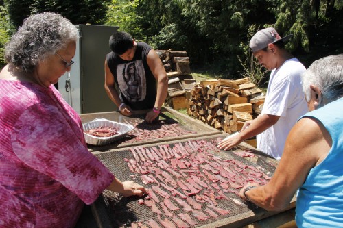Inez Bill-Gobin, Donald Jones, and others peel smoked deer off of the racks after they smoked for a few hours.Photo: Andrew Gobin/Tulalip News