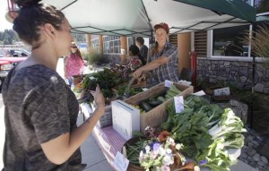 Nisqually Community Market Production Supervisor Carlin Briner helps a customer July 10th at their stand next to the tribal administration building. The tribe's community garden and weekly farm stand provides fresh produce for tribal and community members each week as members work from 8 a.m. until about noon on Thursday mornings in preparation for the afternoon garden stand which is set up at the tribal administration building near Yelm. STEVE BLOOM — The Olympian