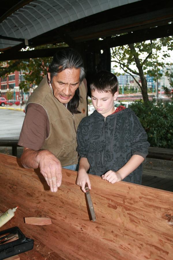Richard WalkerSaaduuts Peele, a Haida master carver, instructs Gabriel Port, a Samish Nation descendant, on a finer point of canoe carving on October 23, 2010, at the Center for Wooden Boats in Lake Union, Seattle. Saaduuts is resident carver at the center, and has carved two canoes with the assistance of local students.