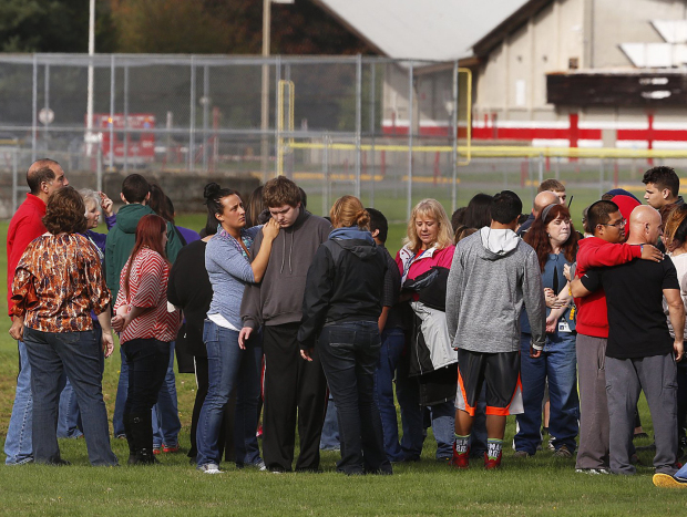 Students and faculty stand on a playing field outside Marysville-Pilchuck HS following a shooting at the school this morning. (Photo by Mark Harrison / The Seattle Times)