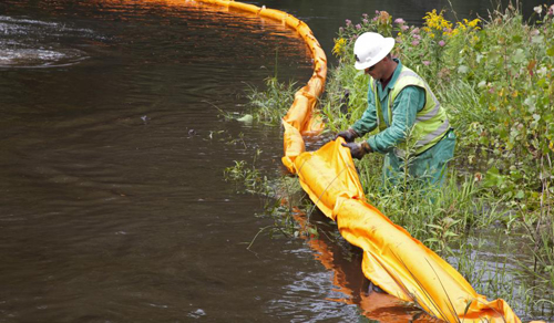 A worker places a containment boom on the Kalamazoo River to contain an oil spill on July 28, 2010. JIM WEST/ZUMA