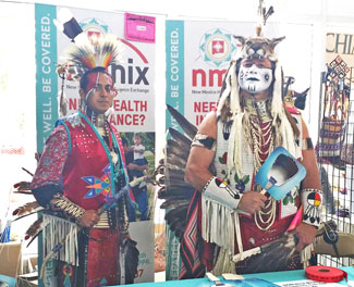 Two dancers in regalia work a Native American Professional Parent Resources outreach booth at the 2014 Gathering of Nations powwow in Albuquerque, N.M. | Courtesy Photo