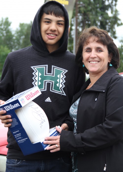 Rochele Hammond presents the signed Michael Bennett football to Nate Hatch. Hatch donated the football to the Tulalip Boys & Girls Club Auction to help raise funds for the club's program. Photo/ Brandi N. Montreuil, Tulalip News