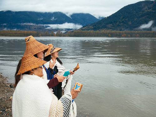 Members of the Tulalip Tribe sing along the banks of the Fraser River in Chilliwack, British Columbia, as part of a ceremony to honor the waters and marine life so integral to the Coast Salish way of life.CHRIS JORDAN-BLOCH / EARTHJUSTICE