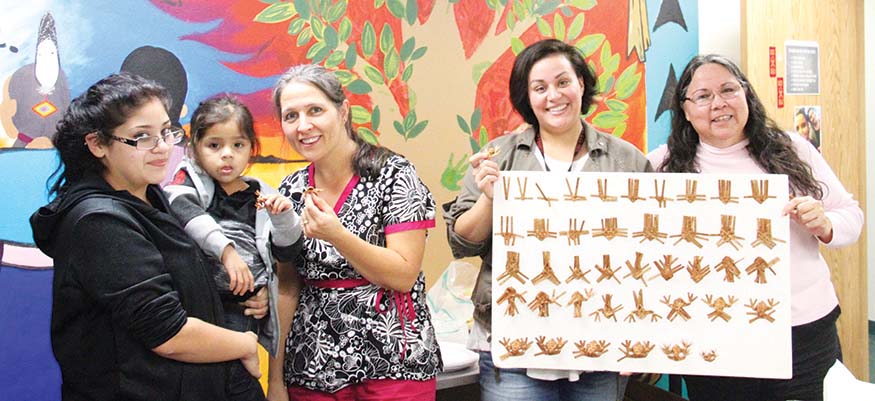 Ashley Tiedeman, Tulalip Tobacco Cessation Program Coordinator (2nd from right), and program members show the woven cedar frog pins they made during a habit replacement class.